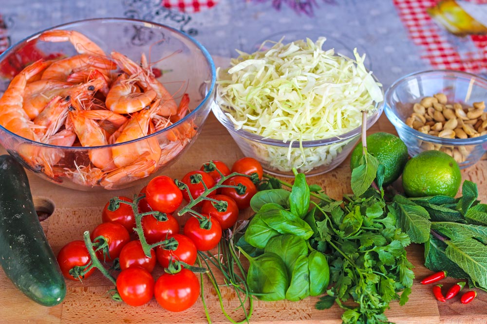Thai prawn salad ingredients - prawns, cucumber, cherry tomatoes, cabbage, basil, coriander mint, chilies